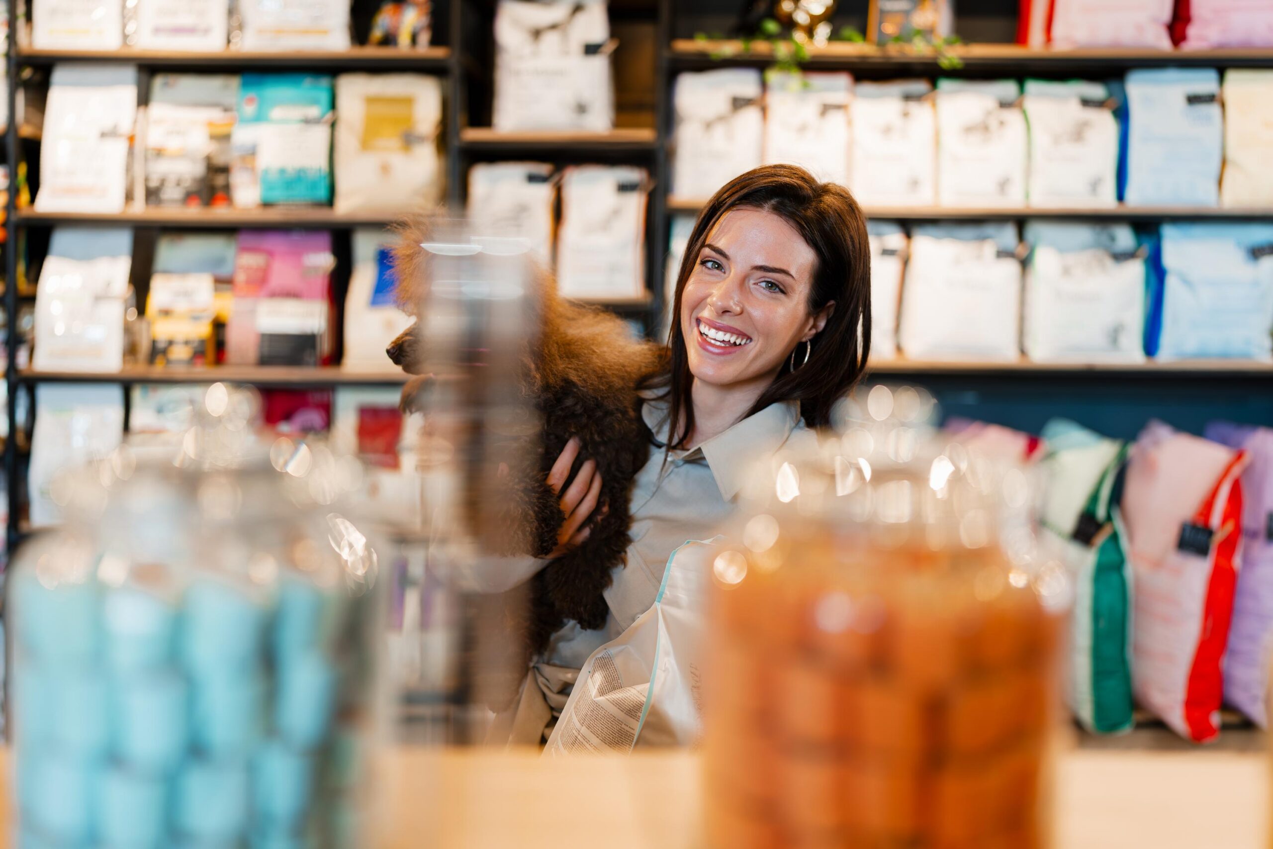 Joyful young woman shopping with her poodle at modern pet store