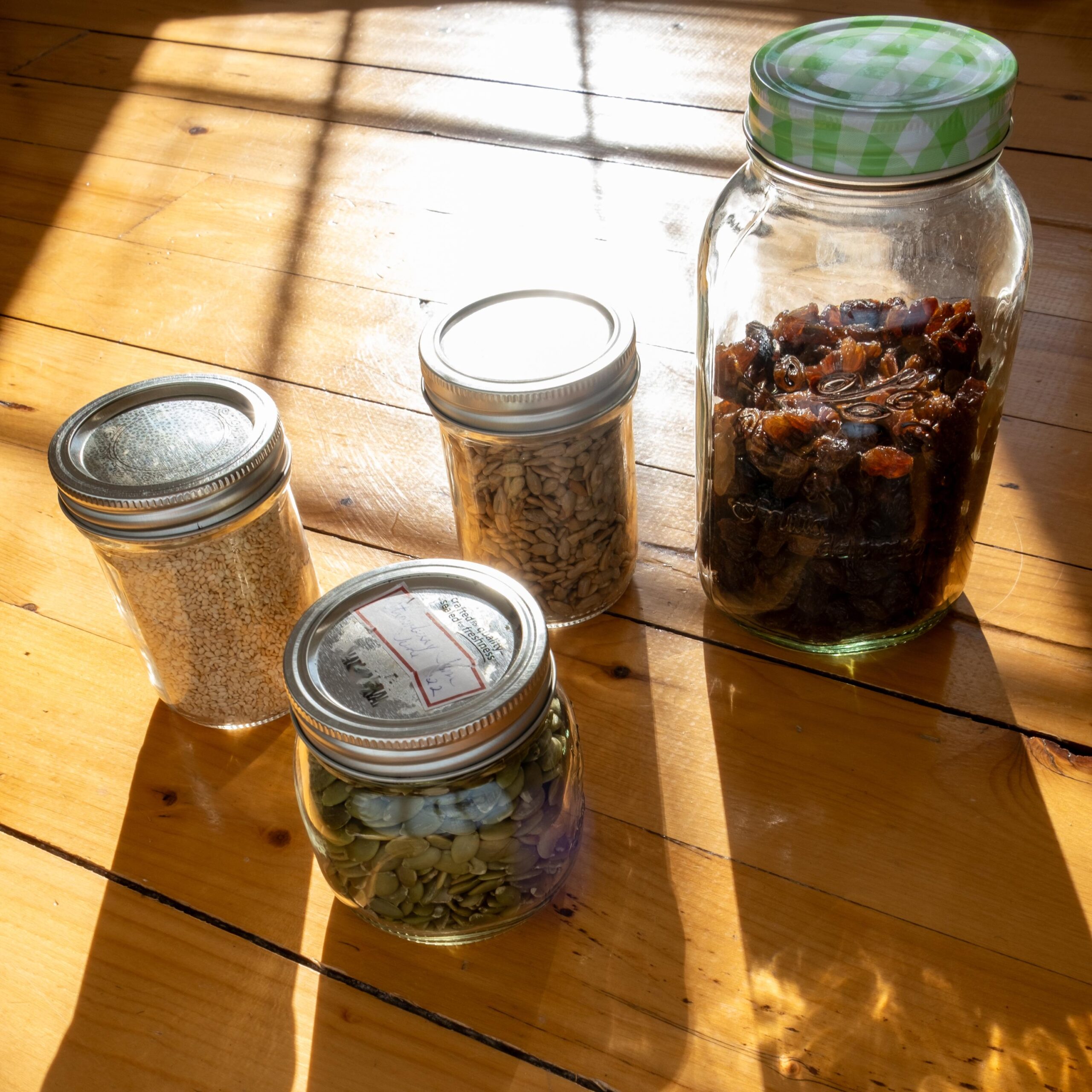 Collection of Edible Seeds and Dried Fruit in Glass Jars on a Wooden Counter Top